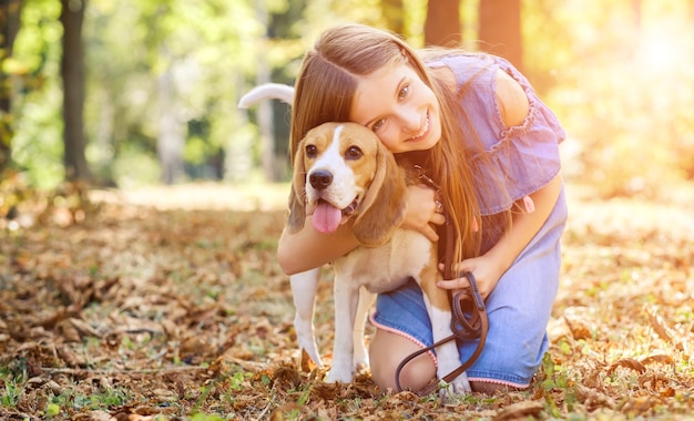 Vrolijk kind dat een hond knuffelt in het zomerbos