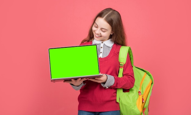 Vrolijk kind dat laptop presenteert met kopieerruimte op rode achtergrond