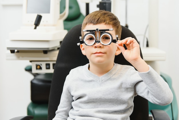 Foto vrolijk kind jongen in glazen controleert oog visie pediatrische oogarts.
