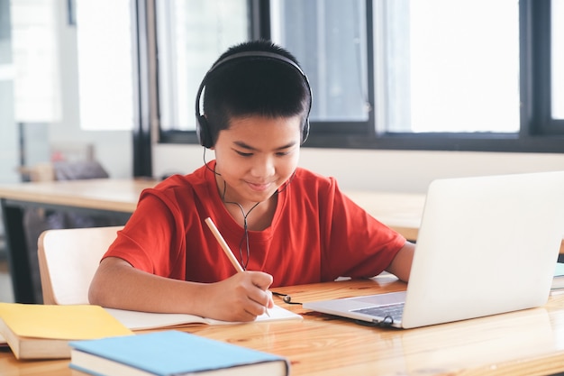 Vrolijk kind opgewonden met behulp van computer voor online leren. Online onderwijs en zelfstudie en homeschooling-concept.