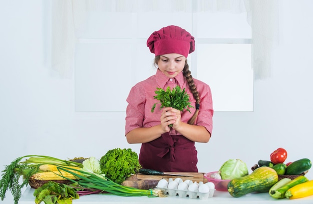 Vrolijk kindmeisje dat vitaminesalade uit de groentenkeuken kookt