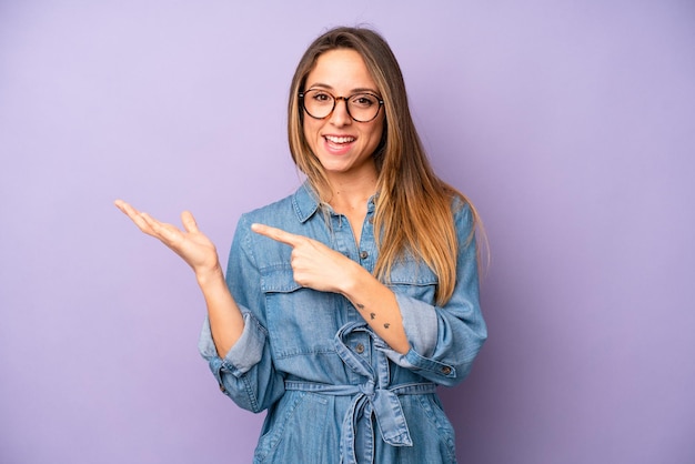 Vrolijk lachend en wijzend naar kopieerruimte op de handpalm aan de zijkant die een object laat zien of er reclame voor maakt