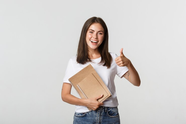Foto vrolijk lachend meisje met notebooks en thumbs-up te tonen