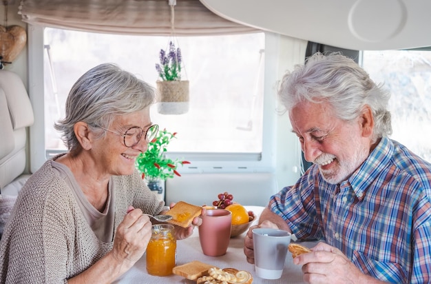 Vrolijk lachend senior koppel in reisvakantie vrije tijd in een camper van dinette die samen van het ontbijt geniet