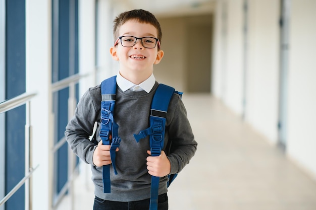 Vrolijk lachende kleine jongen met grote rugzak die plezier heeft schoolconcept back to school