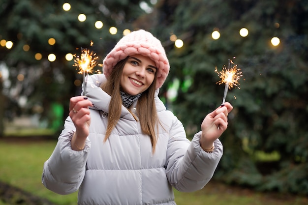 Vrolijk lachende vrouw die plezier heeft met sterretjes in de buurt van de nieuwjaarsboom