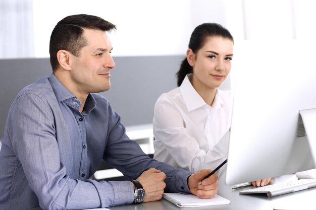 Vrolijk lachende zakenman en vrouw die werkt met computer in moderne kantoren. Headshot op vergadering of werkplek. Teamwork, partnerschap en bedrijfsconcept.