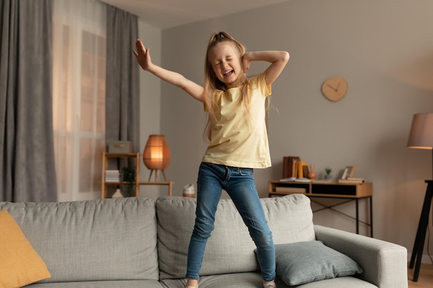 Vrolijk meisje dansen zingen staande op de Bank thuis