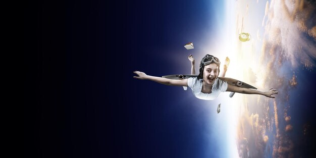Vrolijk meisje dat met zelfgemaakte papieren vleugel in de ruimte vliegt. Gemengde media