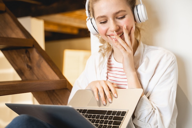 Foto vrolijk meisje dat positiviteit uitdrukt terwijl ze naar het scherm van haar laptop kijkt