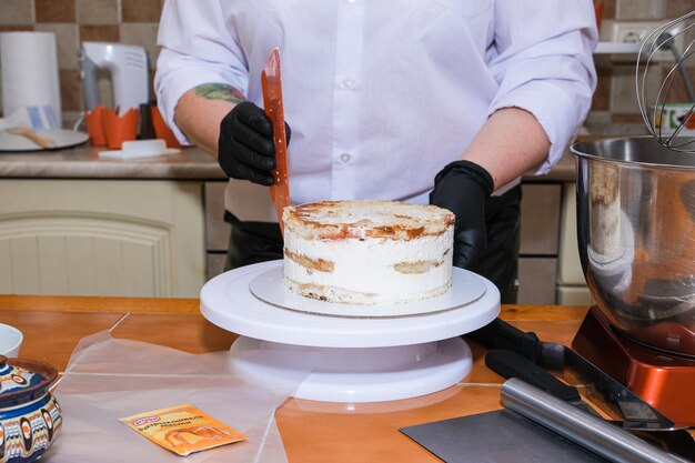 Vrolijk meisje gebruikt een gladder tijdens het bakken van cake in de keuken