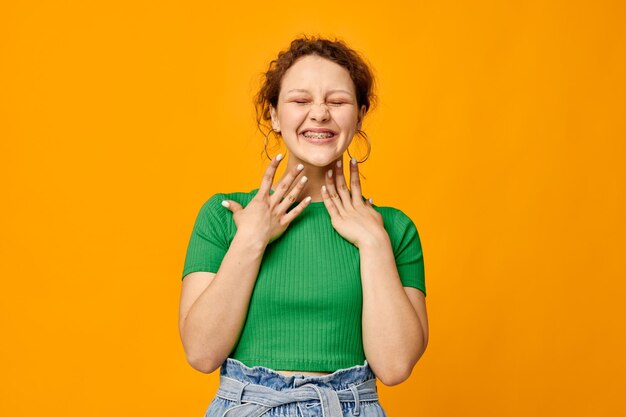 Foto vrolijk meisje in een groene tshirt poseren gebaar handen gele achtergrond