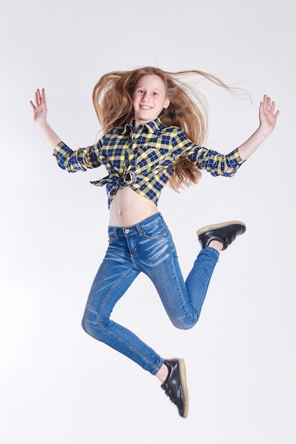 Vrolijk meisje in shirt en spijkerbroek springt