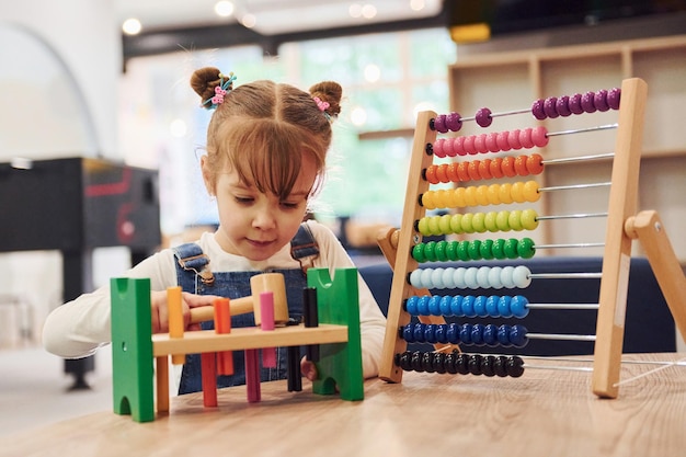 Vrolijk meisje in vrijetijdskleding spelen in de kleuterschool met speelgoed