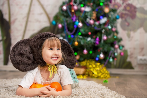 Vrolijk meisje kind gekleed in een carnaval kostuum oren aap, in de buurt van de kerstboom, kerstcadeau vakantie en plezier