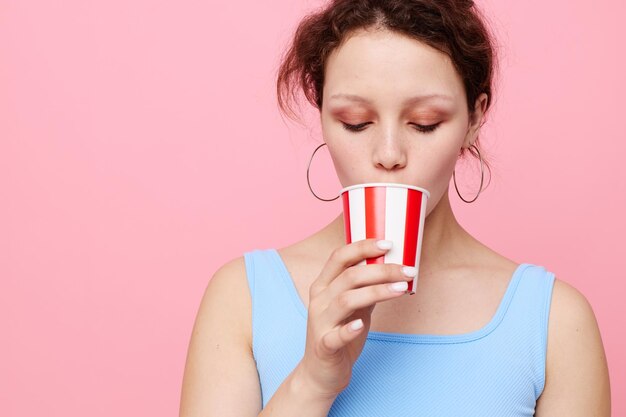 Vrolijk meisje met een veelkleurig wegwerpglas op een roze achtergrond