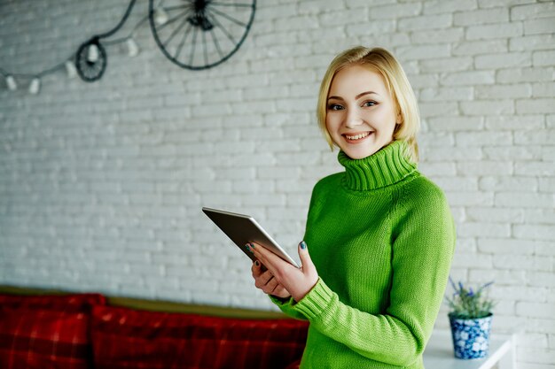 Vrolijk meisje met licht haar dragen groene trui zitten in café met tablet, freelance concept, online winkelen, portret.