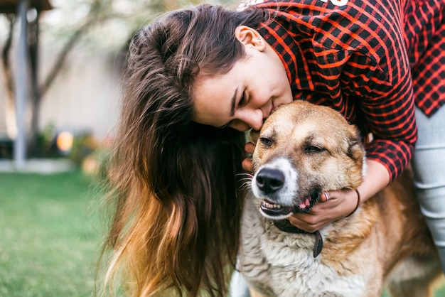 Vrolijk meisje speelt met haar hond in de tuin van het huis in het voorjaar