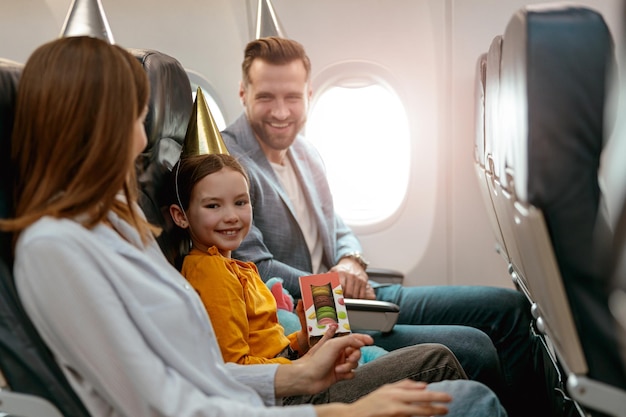 Foto vrolijk meisje viert verjaardag met ouders in vliegtuig