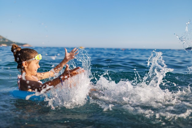 Vrolijk meisje zit in een opblaasbare cirkel en spettert met water in de zee