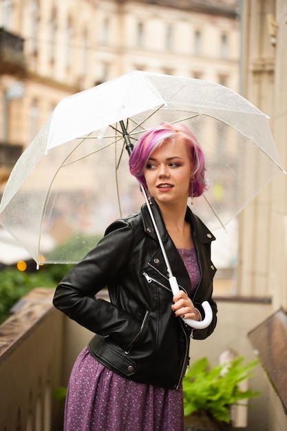 Vrolijk mooi meisje dat paraplu vasthoudt terwijl ze naar buiten wandelt Ze draait zich om en kijkt naar ca
