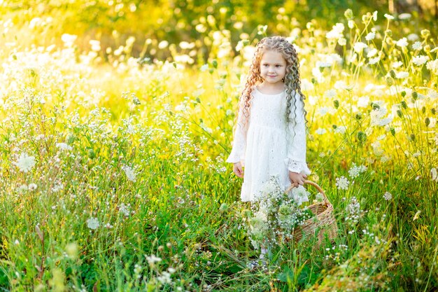 Vrolijk mooi meisje in een strooien hoed in een geel veld met bloemen