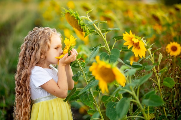 Vrolijk mooi meisje in een strooien hoed in een geel veld met bloemen