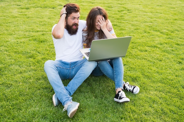 Vrolijk paar gebruiken laptop sit groen gras schokkend concent concept