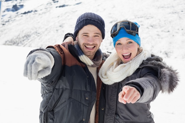 Vrolijk paar in jasjes die op camera op sneeuw behandeld landschap richten