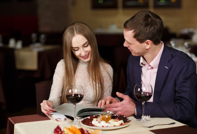 Vrolijk paar met menu in een restaurant.