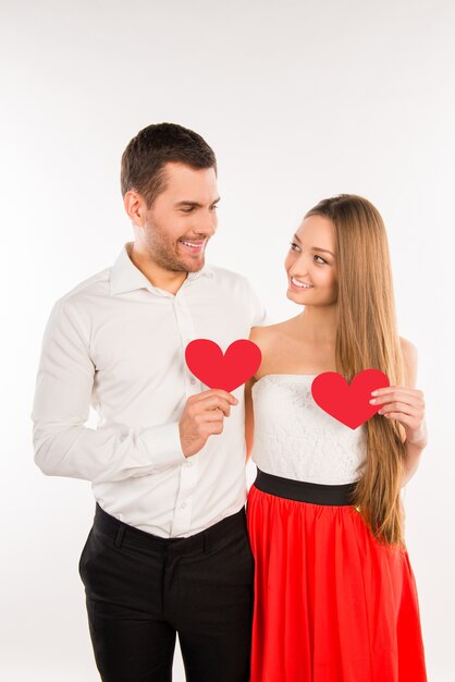 Vrolijk paar verliefd met twee rode papieren harten