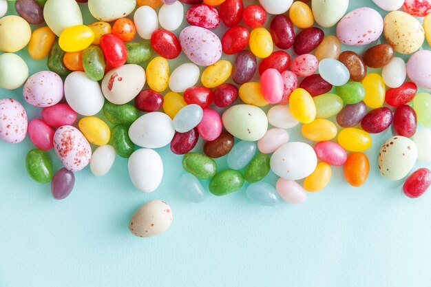 Vrolijk Pasen concept. Voorbereiding op vakantie. Pasen snoep chocolade-eieren en jellybean snoep geïsoleerd op trendy pastel blauwe achtergrond. Eenvoudig minimalisme plat lag bovenaanzicht kopie ruimte.