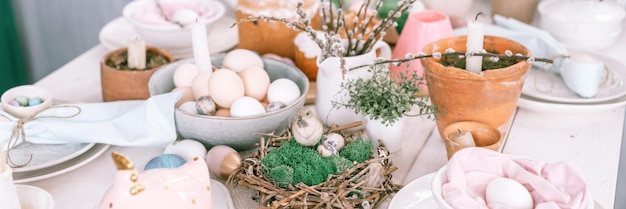 Vrolijk pasen en voorjaarsvakantie tijd feestelijk tablescape set decor traditioneel diner eten paaseieren en gebakken taarten op tafel thuis konijn en wilg bleke pop pastel blauw roze kleur banner