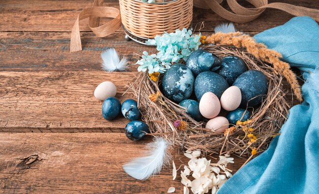 Vrolijk Pasen, feestelijke achtergrond met eieren in een nest op een houten achtergrond.