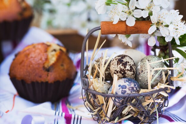 Vrolijk pasen - mand met eieren en cupcakes op de achtergrond van kersenbloesems