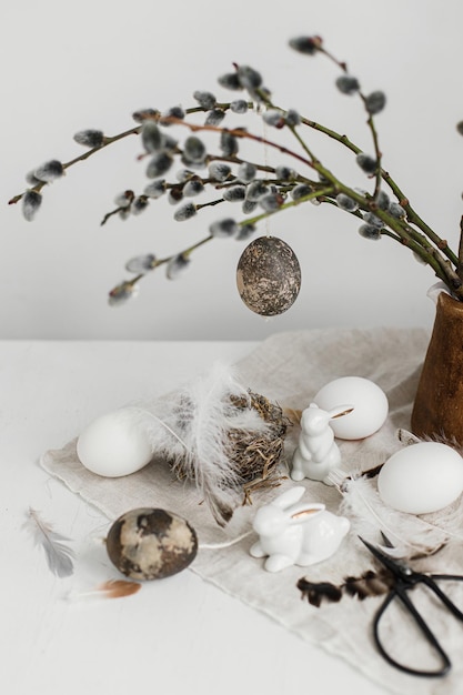 Vrolijk Pasen Natuurlijke eieren konijn beeldjes veren nest wilgentakken in vaas op tafel