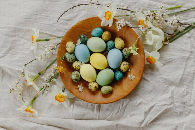 Vrolijk Pasen Rustieke pasen plat leggen Stijlvolle paaseieren en bloeiende lentebloemen in houten kom op rustieke tafel Natuurlijk beschilderde eieren en narcissen op linnen stof