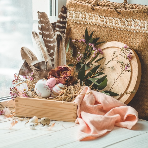 Vrolijk pasen tafel. roze paaseieren in een nest met florale decoraties en veren in de buurt van het venster