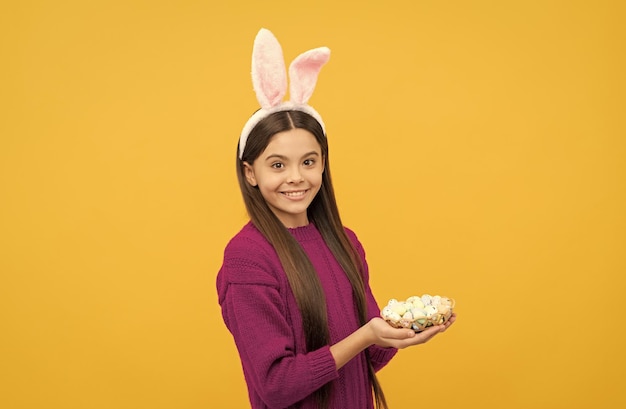 Vrolijk Pasen tienermeisje in grappige konijnenoren houdt beschilderde kwarteleitjes vast vrolijk Pasen