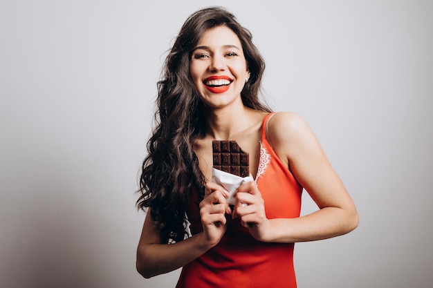 Vrolijk schattig donkerbruin meisje heeft een hap chocolade genomen