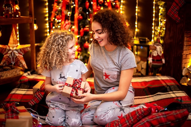 Vrolijk schattig krullend meisje en haar oudere zus die geschenken uitwisselen.