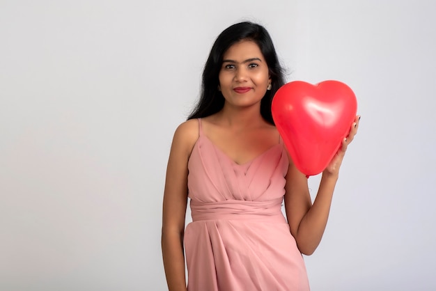 Vrolijk schattig meisje in mooie outfit poseren met hartvorm ballon