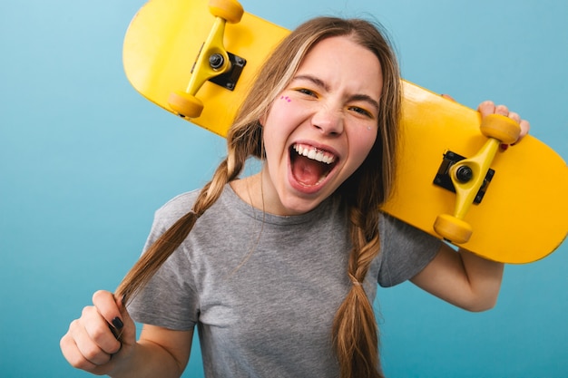 Vrolijk schattig meisje permanent geïsoleerd, skateboard te houden