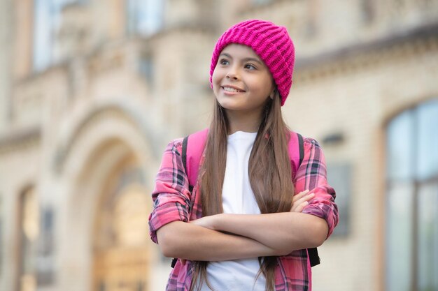 Vrolijk schoolkind gekruiste handen met rugzak