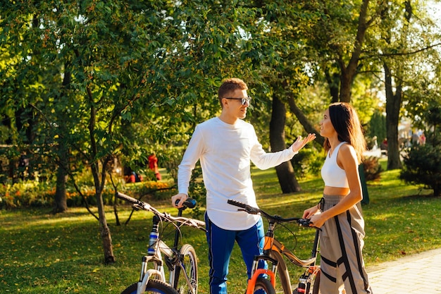 Vrolijk sportief stel heeft een praatje en rust in het park op hun fiets