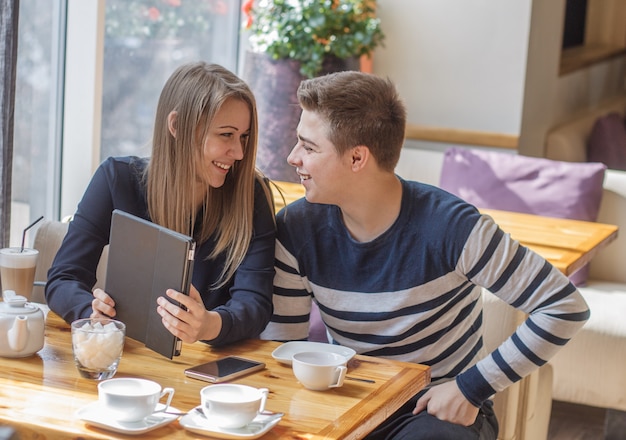 Vrolijk stel dating in een café Ze hebben plezier en lachen met tablet