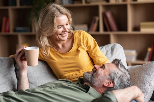 Vrolijk stel van middelbare leeftijd dat samen thuis koffie drinkt en kletst