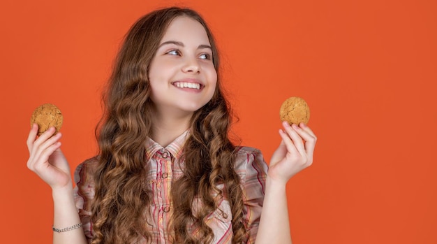 Vrolijk tienerkind met havermoutkoekjes op oranje achtergrond