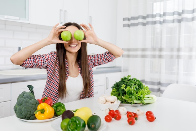 Vrolijk vegetarisch meisje poseren aan een tafel met veel groenten