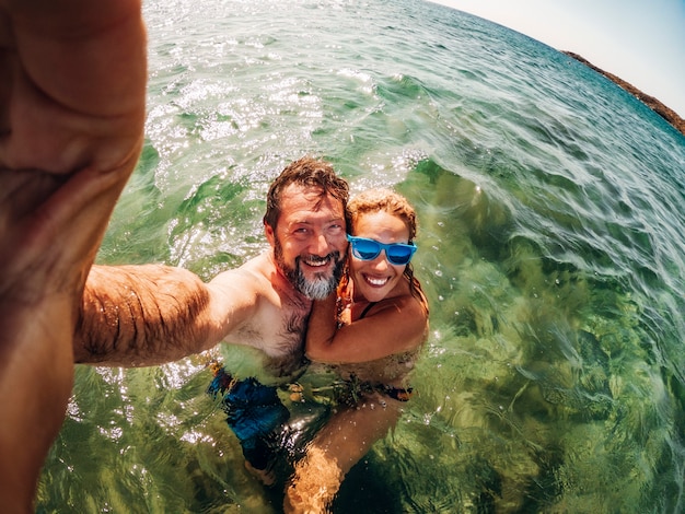 Foto vrolijk volwassen stel neemt selfie foto's zwemmen in de zee en genieten van de zomer